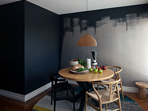 Deep moody dining room with grunge paint timber table and floor with rug and hanging lamp